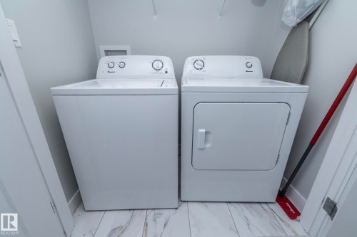Dedicated laundry area featuring a white washing machine and a white dryer, with a white and gray tiled floor - 20650 94A Avenue, Edmonton, AB - Indoor Photo Showing Laundry Room