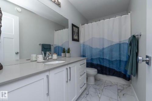 Bathroom featuring a vanity with a light-colored countertop, an undermount sink, and white cabinetry with brushed nickel hardware - 20650 94A Avenue, Edmonton, AB - Indoor Photo Showing Bathroom