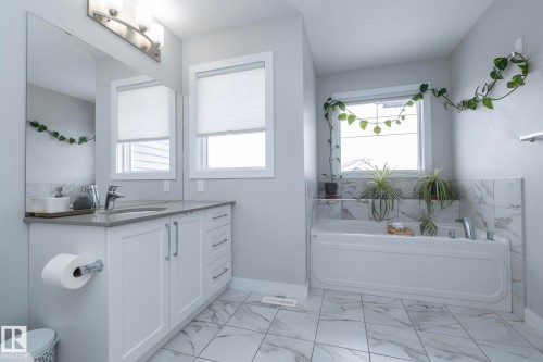 Bathroom featuring a white vanity with a gray countertop, a large mirror, and a white bathtub - 20650 94A Avenue, Edmonton, AB - Indoor Photo Showing Bathroom