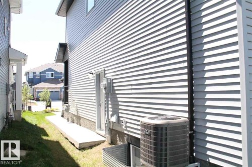 The property features light-colored horizontal siding, a visible air conditioning unit, and a window well, indicating a basement - 20650 94A Avenue, Edmonton, AB - Outdoor