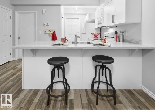 The kitchen features white cabinetry, a light-colored countertop, and a stainless steel sink, with a light wood-look floor - 20650 94A Avenue, Edmonton, AB - Indoor Photo Showing Kitchen