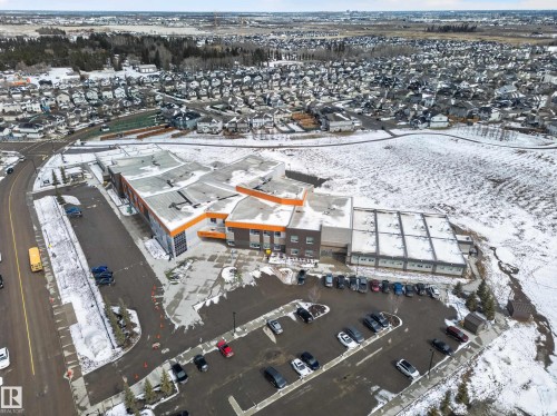 Aerial view of a community featuring residential properties, a large building with an orange roof, and a parking lot - 20650 94A Avenue, Edmonton, AB - 