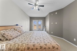 This room features a vaulted ceiling with a ceiling fan, carpeted flooring, and a set of double glass doors - 