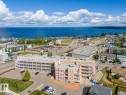 The property features a multi-story building with balconies, surrounded by a paved parking area and landscaped green spaces - 107 801 11 Street, Cold Lake, AB  - Outdoor With Body Of Water With View 