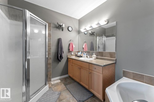The bathroom features a walk-in shower with a glass door, a vanity with a countertop and under-sink storage, and a built-in bathtub - 107 801 11 Street, Cold Lake, AB - Indoor Photo Showing Bathroom