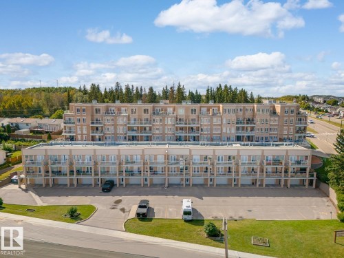 The property features a multi-story building with numerous balconies, a paved parking area, and well-maintained green spaces - 107 801 11 Street, Cold Lake, AB - Outdoor With View
