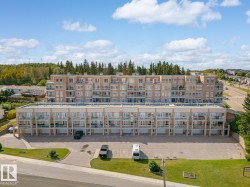 The property features a multi-story building with numerous balconies, a paved parking area, and well-maintained green spaces - 