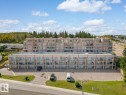 The property features a multi-story building with numerous balconies, a paved parking area, and well-maintained green spaces - 107 801 11 Street, Cold Lake, AB  - Outdoor With View 