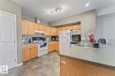 The kitchen features light-toned wooden cabinetry, an integrated double sink, and tiled flooring - 107 801 11 Street, Cold Lake, AB  - Indoor Photo Showing Kitchen With Double Sink 