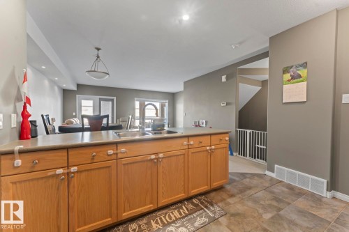 Kitchen featuring an island with a double basin sink, light wood cabinetry, and tiled flooring - 107 801 11 Street, Cold Lake, AB - Indoor Photo Showing Kitchen