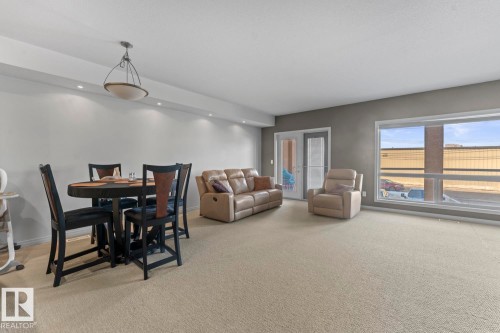 Spacious open-concept room featuring light-colored carpeting, large windows, and a glass-paneled door - 107 801 11 Street, Cold Lake, AB - Indoor