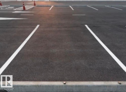 Paved parking area featuring white parking space lines and a concrete parking curb - 9363 Simpson Drive Nw, Edmonton, AB 
