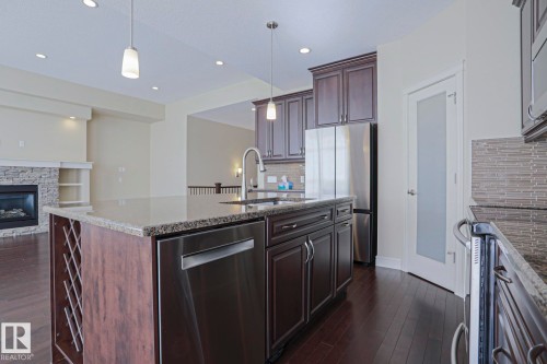 The kitchen features dark wood cabinetry, stainless steel appliances, a center island with a granite countertop and integrated sink, and recessed lighting - 2315 Ashcraft Cape, Edmonton, AB - Indoor Photo Showing Kitchen With Upgraded Kitchen