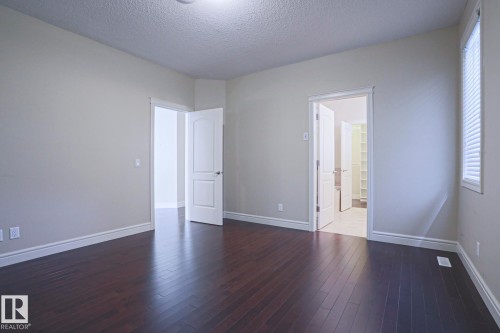 The property features dark hardwood flooring, light-colored walls, and white trim throughout - 2315 Ashcraft Cape, Edmonton, AB - Indoor Photo Showing Other Room