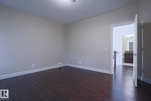 Spacious room featuring dark hardwood floors, light neutral walls, and crisp white baseboards - 2315 Ashcraft Cape, Edmonton, AB - Indoor Photo Showing Other Room