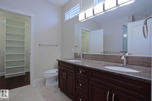 Bathroom featuring a double vanity with granite countertops, two sinks, and dark wood cabinetry - 2315 Ashcraft Cape, Edmonton, AB - Indoor Photo Showing Bathroom