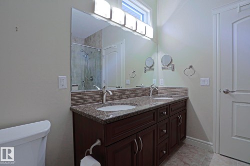 The bathroom features a double vanity with a granite countertop, undermount sinks, and a tiled backsplash - 2315 Ashcraft Cape, Edmonton, AB - Indoor Photo Showing Bathroom