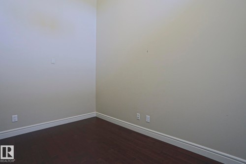 This room features dark hardwood flooring and light-colored walls with white baseboards - 2315 Ashcraft Cape, Edmonton, AB - Indoor Photo Showing Other Room