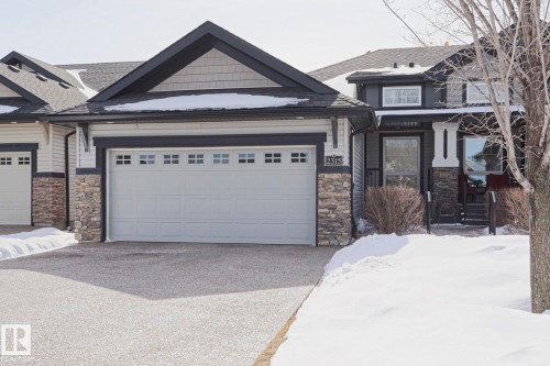 The property features a two-car garage with individual doors, a stone facade, and a paved driveway - 2315 Ashcraft Cape, Edmonton, AB - Outdoor With Facade