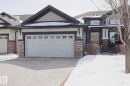 The property features a two-car garage with individual doors, a stone facade, and a paved driveway - 2315 Ashcraft Cape, Edmonton, AB  - Outdoor With Facade 