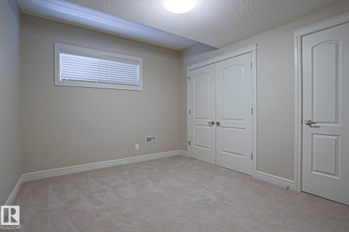 This room features light-colored carpeting, a window with blinds, and white doors with silver hardware - 2315 Ashcraft Cape, Edmonton, AB - Indoor Photo Showing Other Room