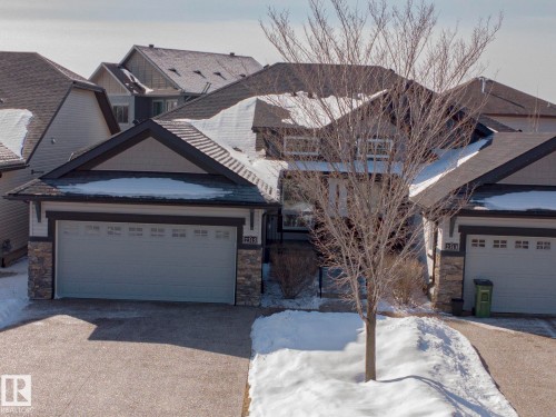 The property features a two-car garage, a paved driveway, and a front exterior with stone accents and siding - 2315 Ashcraft Cape, Edmonton, AB - Outdoor