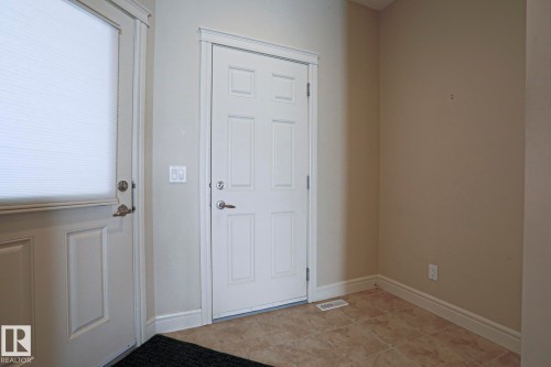 Entryway featuring neutral wall paint, tile flooring, and white doors with matching trim - 2315 Ashcraft Cape, Edmonton, AB - Indoor Photo Showing Other Room