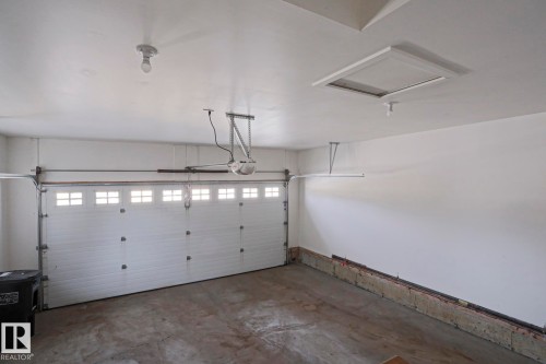 This garage features a white panel garage door with windows, a concrete floor, and overhead lighting - 2315 Ashcraft Cape, Edmonton, AB - Indoor Photo Showing Garage