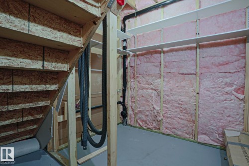 The property features a utility area with exposed wood framing, insulation, and shelving - 2315 Ashcraft Cape, Edmonton, AB - Indoor