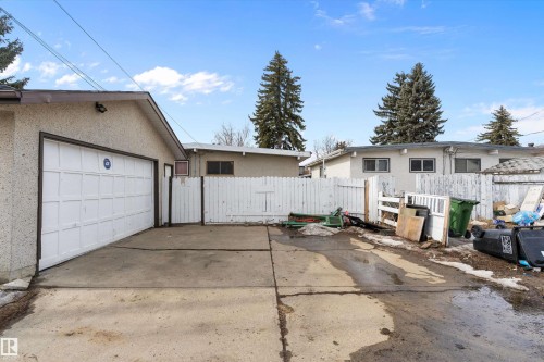 The property features a concrete driveway and an attached garage with a white panel door - 6103-6105 97A Avenue, Edmonton, AB - Outdoor