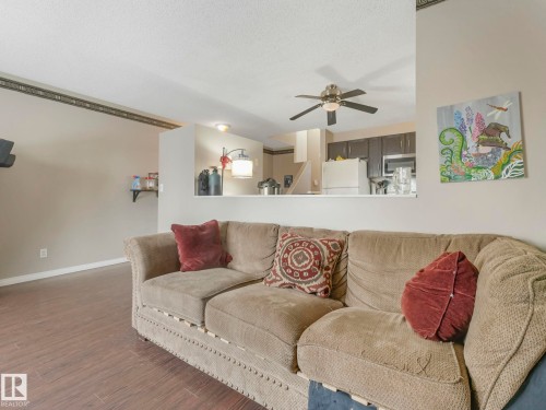 Living area featuring hard surface flooring, a ceiling fan with light, and a pass-through opening to the kitchen - 4105 41 Avenue, Edmonton, AB - Indoor Photo Showing Living Room