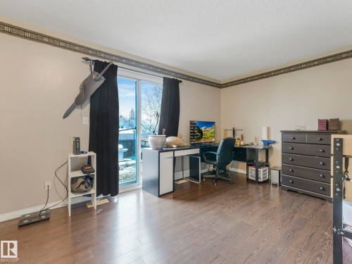 This room features wood-look flooring and a sliding glass door providing access to the outdoors - 4105 41 Avenue, Edmonton, AB - Indoor Photo Showing Office