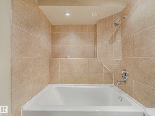 Bathroom featuring a white bathtub, tiled walls, a shower fixture, and recessed lighting - 4105 41 Avenue, Edmonton, AB - Indoor Photo Showing Bathroom