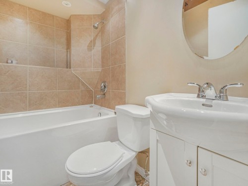 Bathroom with a white bathtub and shower featuring tiled walls, a white toilet, and a white sink with a vanity - 4105 41 Avenue, Edmonton, AB - Indoor Photo Showing Bathroom