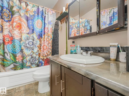 Bathroom with a white toilet, a white sink set into a dark vanity, and a mirrored cabinet - 4105 41 Avenue, Edmonton, AB - Indoor Photo Showing Bathroom