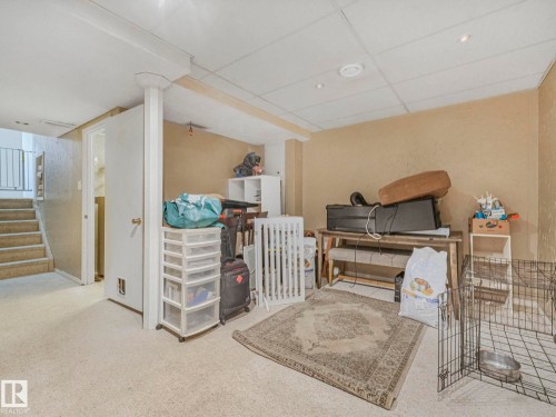 The property features a carpeted room with a staircase, a white door, and neutral-toned walls - 4105 41 Avenue, Edmonton, AB - Indoor Photo Showing Other Room