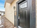 The property features a black exterior door with window panes, a wall-mounted light fixture, and a stucco-textured exterior wall - 4105 41 Avenue, Edmonton, AB  - Outdoor With Exterior 