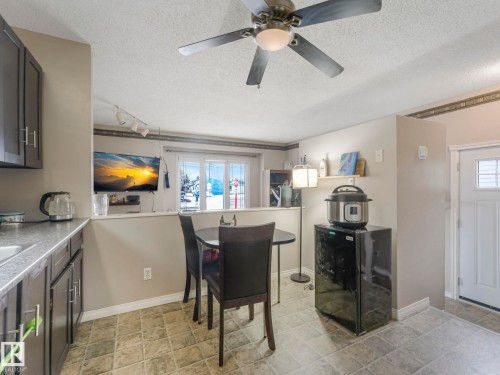 This room features dark cabinetry, textured flooring, and a large window providing natural light - 4105 41 Avenue, Edmonton, AB - Indoor Photo Showing Laundry Room
