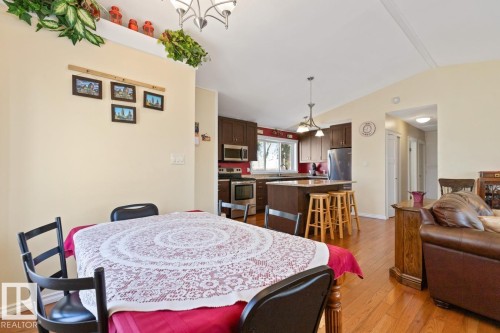 Open-concept living area with hardwood floors, a kitchen featuring dark wood cabinetry, a central island, and stainless steel appliances - 15926 92 Avenue, Edmonton, AB - Indoor Photo Showing Dining Room