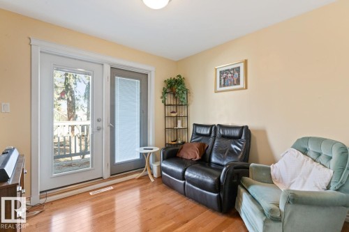 Living area featuring warm-toned walls, hardwood flooring, and direct access to an outdoor area through double doors - 15926 92 Avenue, Edmonton, AB - Indoor Photo Showing Living Room