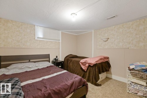 This room features textured wallpaper, wainscoting, and carpeted flooring - 15926 92 Avenue, Edmonton, AB - Indoor Photo Showing Bedroom