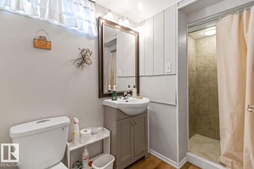 This bathroom features a shower with tiled walls, a vanity with an integrated sink, and a framed mirror - 15926 92 Avenue, Edmonton, AB - Indoor Photo Showing Bathroom