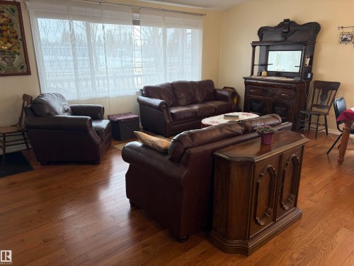 The living area features hardwood flooring and a large window with sheer white curtains - 15926 92 Avenue, Edmonton, AB - Indoor Photo Showing Living Room