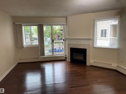 Living space featuring wood-finish flooring, a tiled fireplace with mantel, and a sliding glass door to a balcony - 