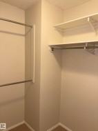 White painted walls in a closet space with multiple hanging rods and white shelving - 