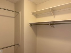 Closet interior featuring two levels of hanging rods and upper shelving - 