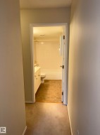 Bathroom featuring a white vanity with built-in storage, a white toilet, and a bathtub with white subway tile surround - 
