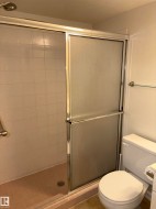Shower enclosure with frosted sliding glass doors, white tiled walls, and a chrome showerhead - 