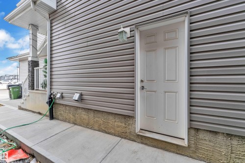 The property features a durable siding exterior, a white panel door, and a concrete pathway - 2630 16A Ave Nw, Edmonton, AB - Outdoor