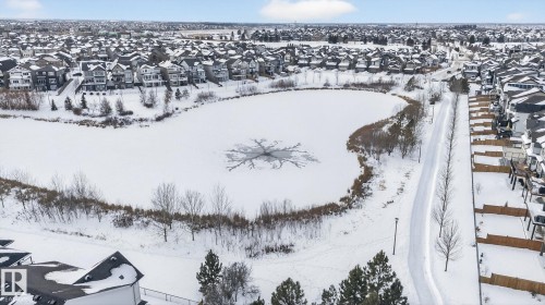 Aerial view showcasing the surrounding neighborhood, featuring a snow-covered pond with visible ice formations, and a paved pathway running alongside the pond - 3230 Parker Loop, Edmonton, AB - Outdoor With View